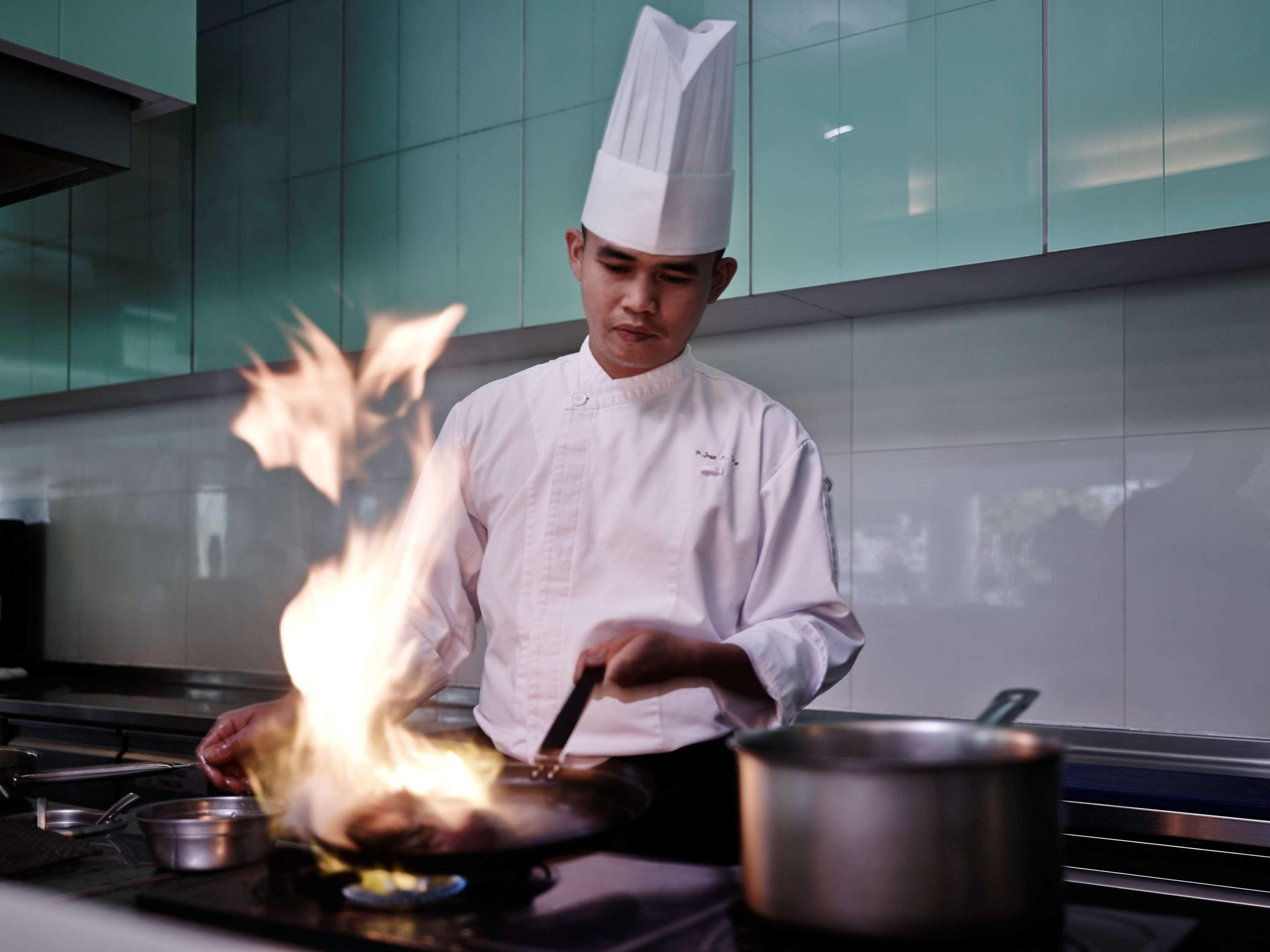 โรงแรมพูลแมน กูชิง ภายนอก รูปภาพ A chef cooking with a flaming wok